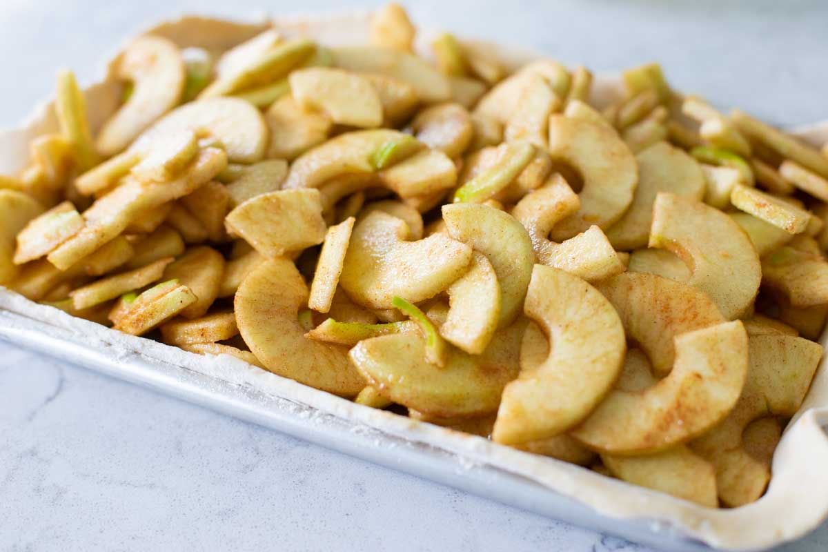 Cinnamon coated apple slices fill a pie pan.