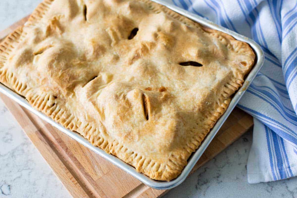 The top crust has been crimped into place and venting holes are sliced into the top.