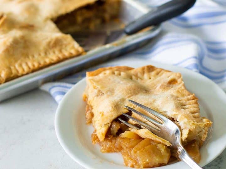A square piece of apple pie has a fork taking a bite.