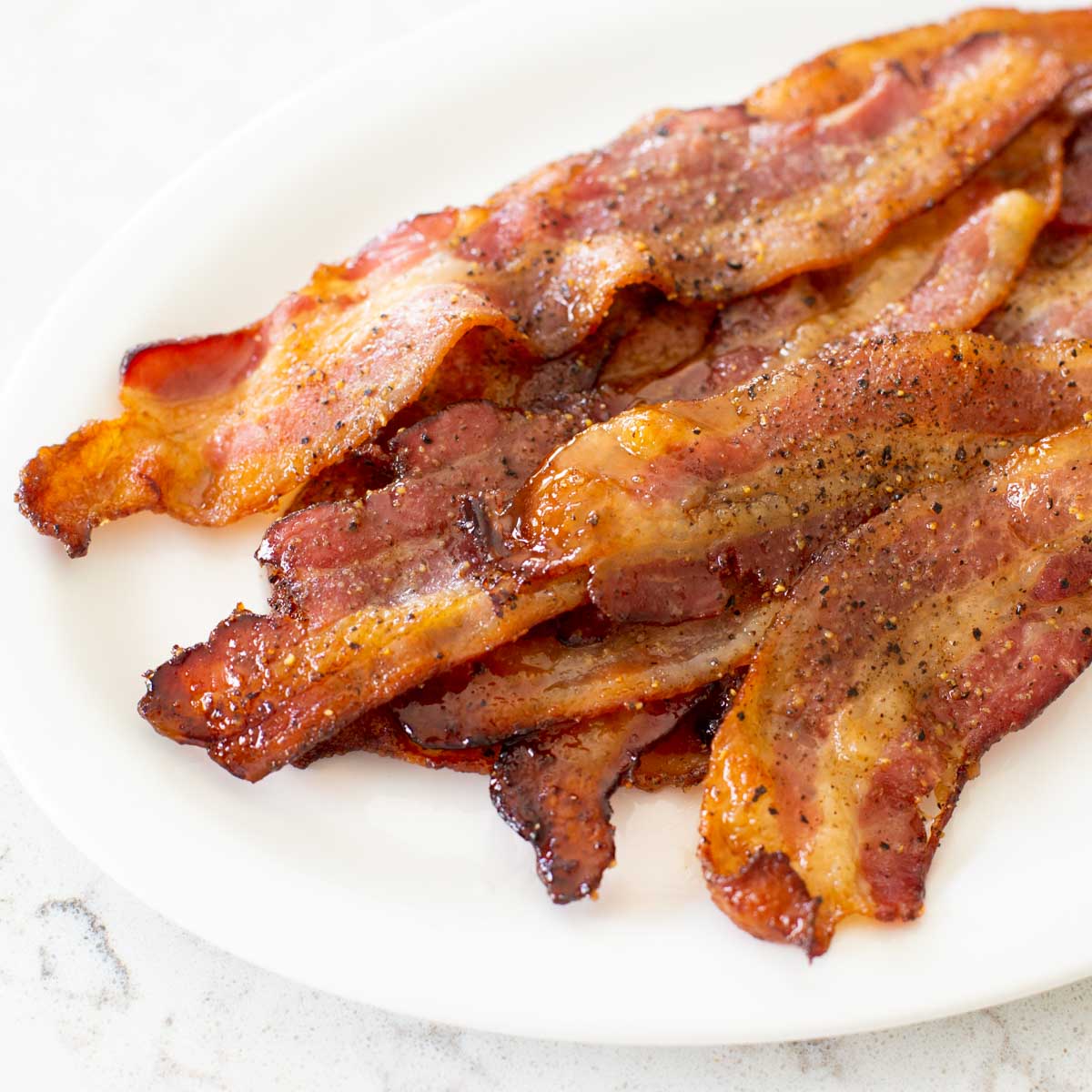 A platter of candied bacon with pepper is ready to serve.