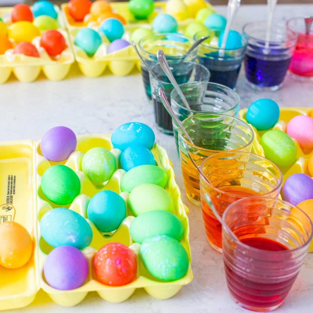 Trays of Easter eggs are being dyed in colorful cups.
