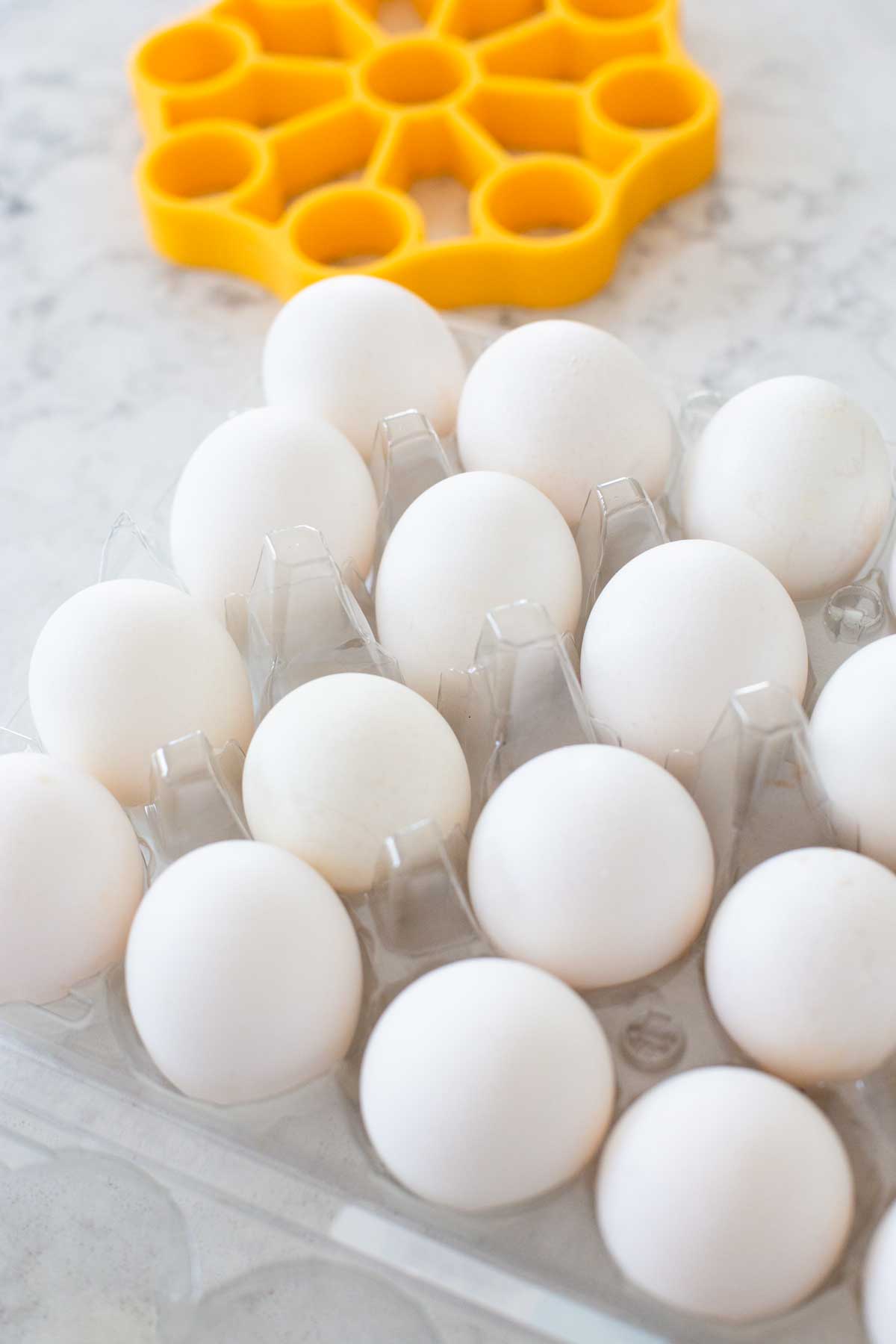 A tray of eggs sit next to a silicone egg rack.