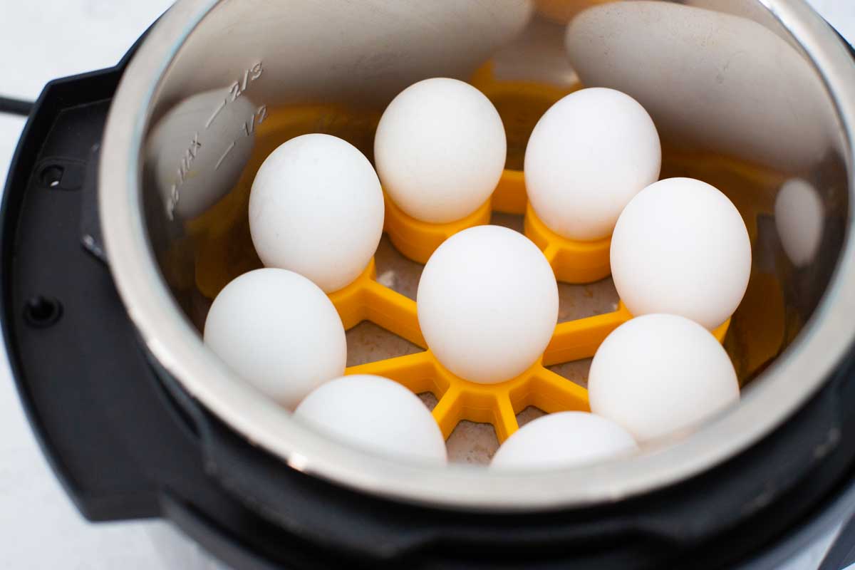 A yellow silicone egg rack has eggs in an Instant Pot.