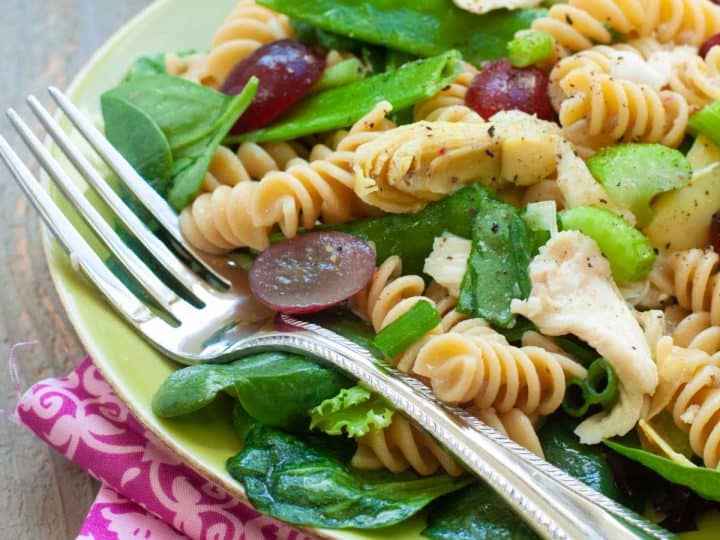 A serving of grape and chicken pasta salad is on a plate with a fork.