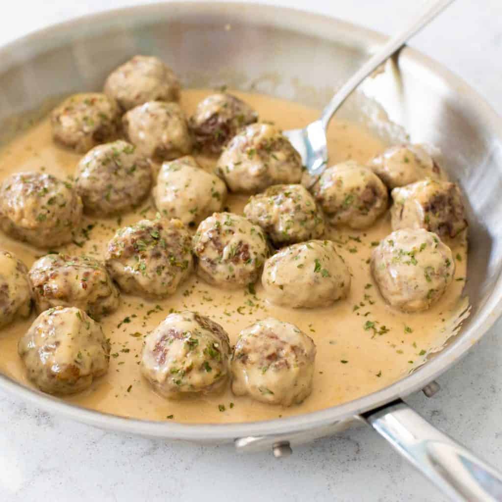 A skillet is filled with Swedish meatballs and creamy gravy.