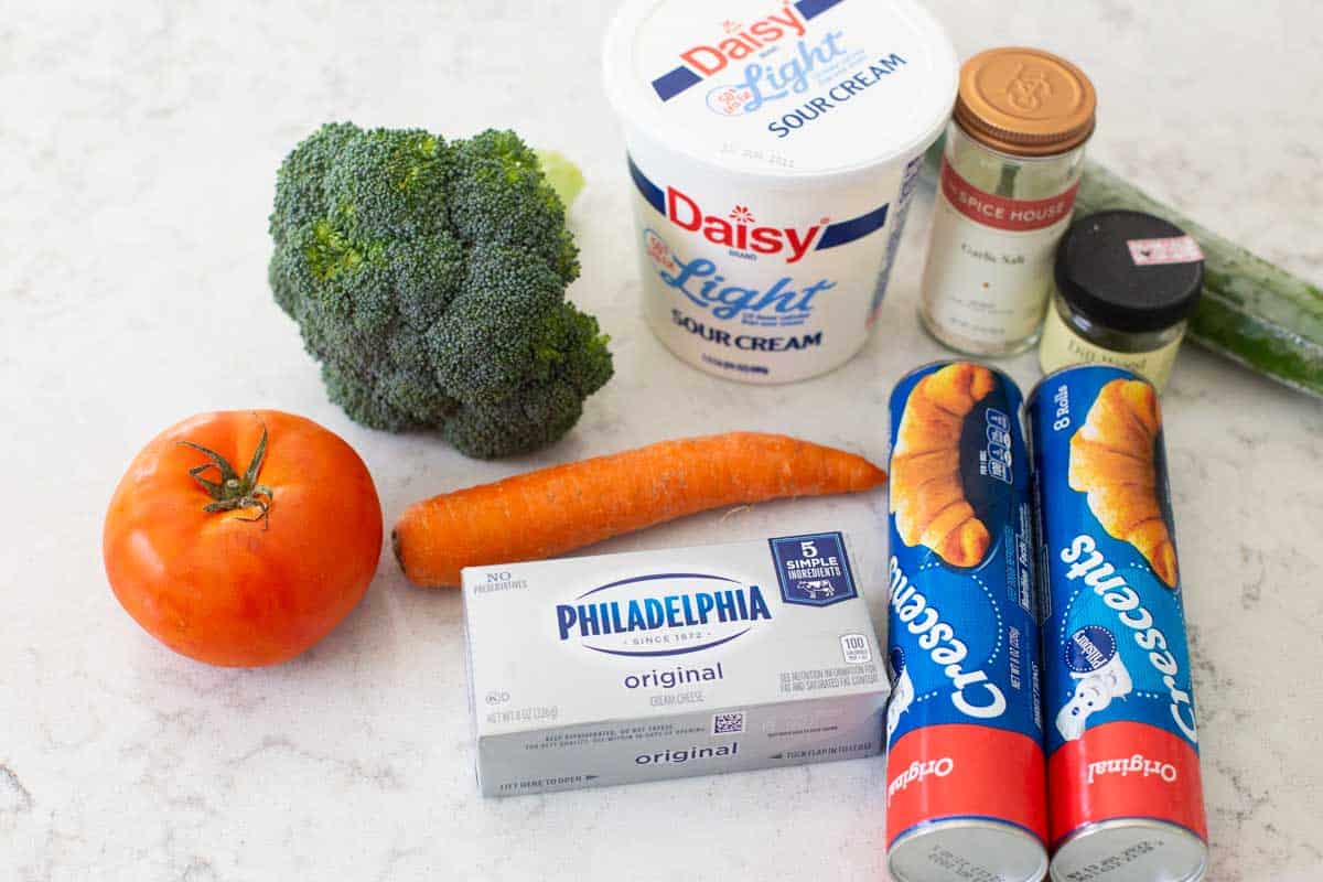 The ingredients to make veggie pizza appetizer are on the counter.