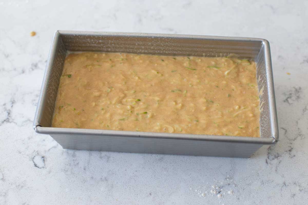 The zucchini bread batter has been smoothed into a quick bread pan.