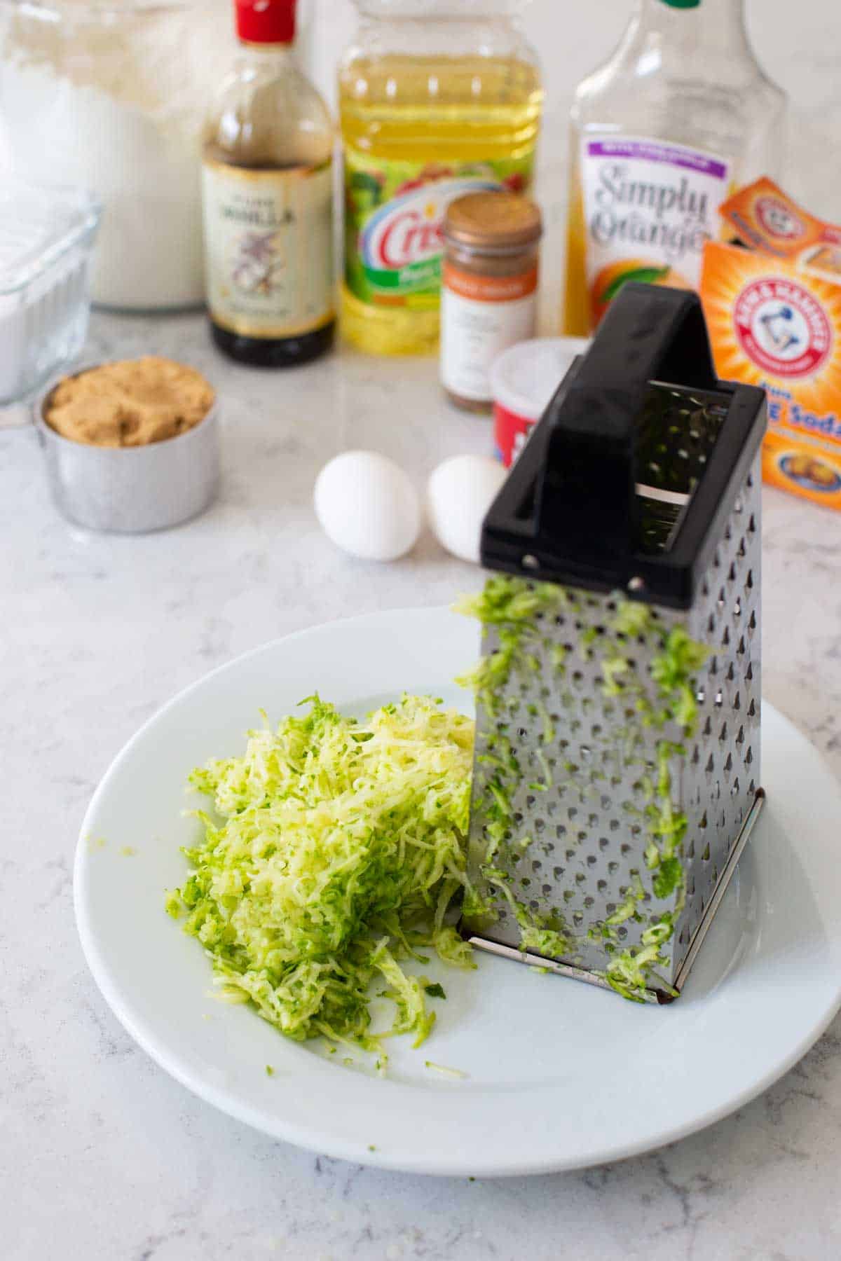 A box grater shows how to prepare the grated zucchini on a plate.