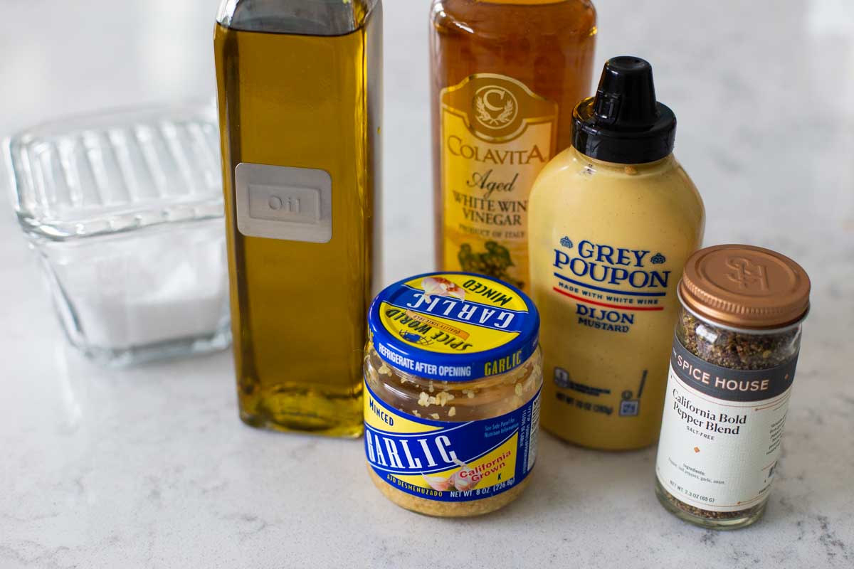 the ingredients to make mustard vinaigrette are on the counter.