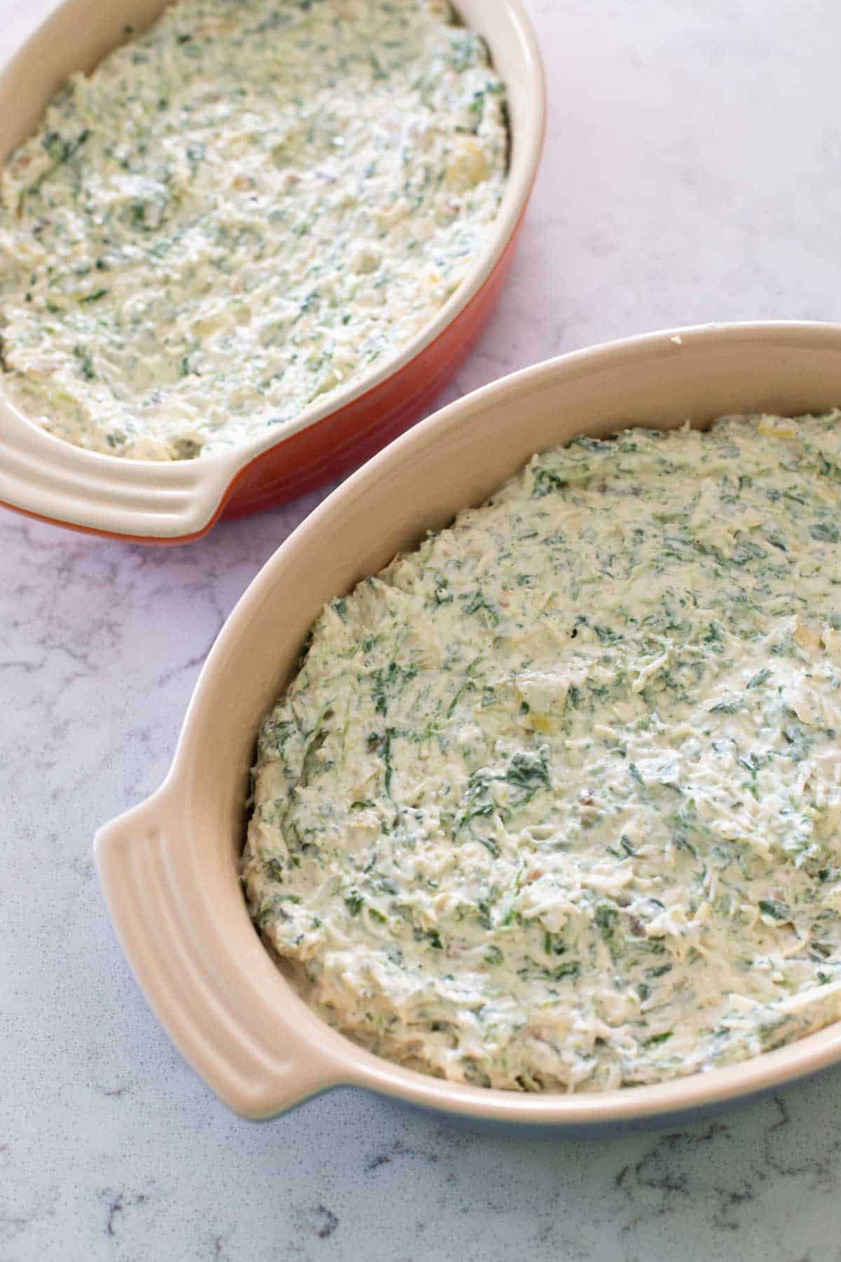 The dip has been spread into two smaller oval baking dishes.