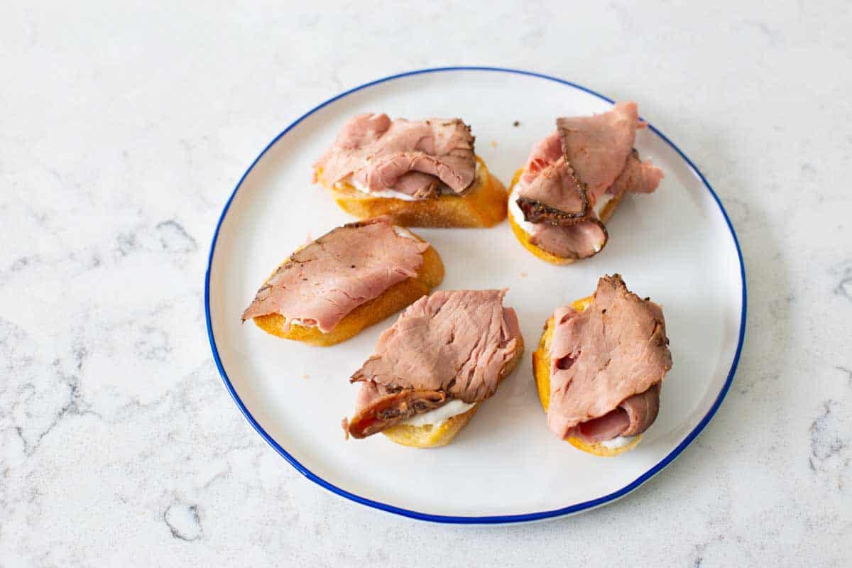 Slices of thick cut roast beef have been added to each crostini.