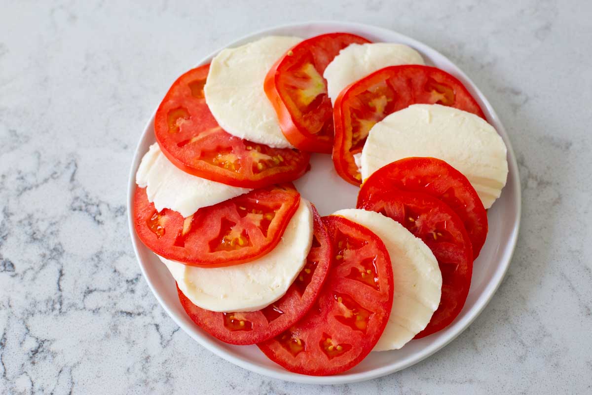 The fresh mozzarella has been tucked between slices of fresh tomato.