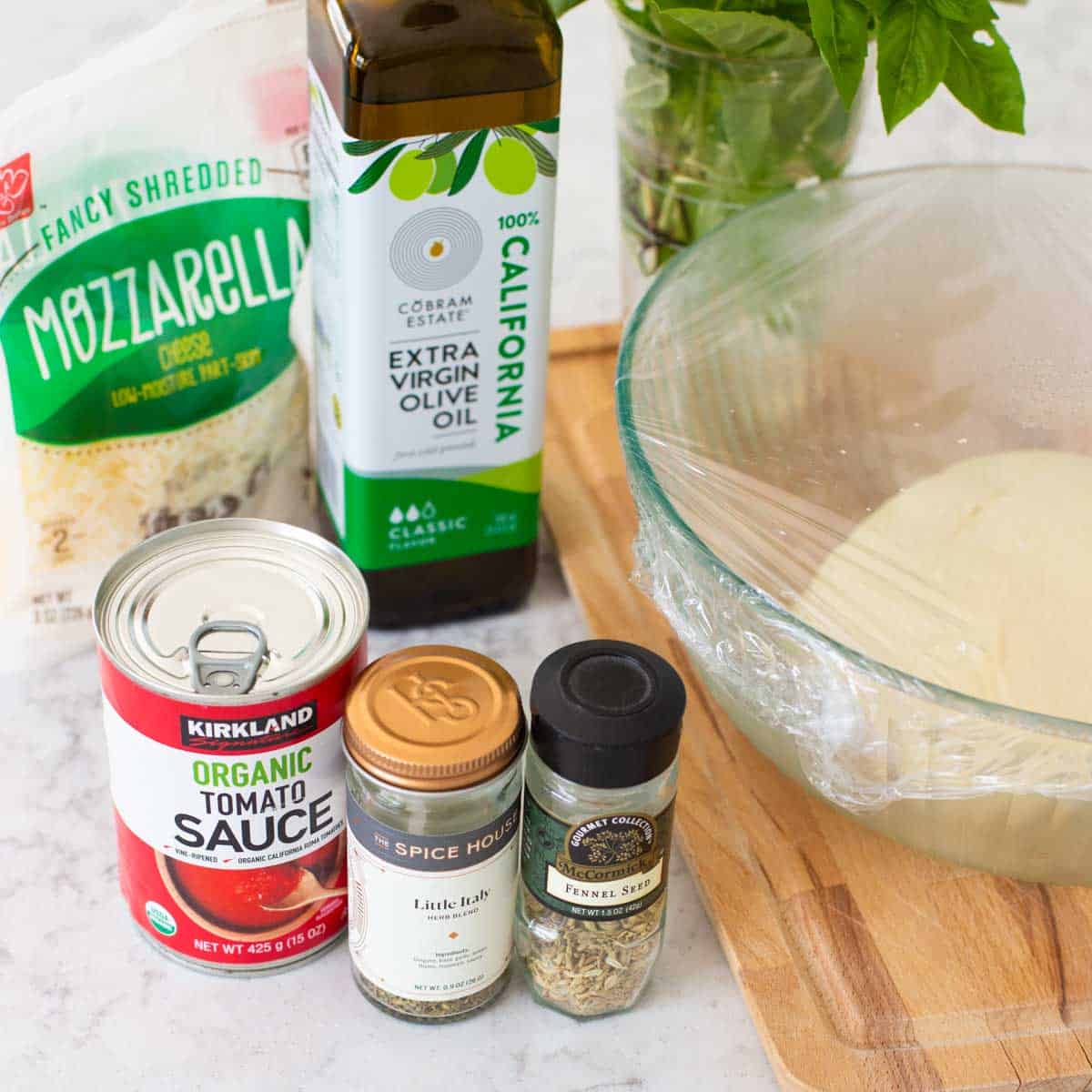 The ingredients to make cheese pizza are on the counter.