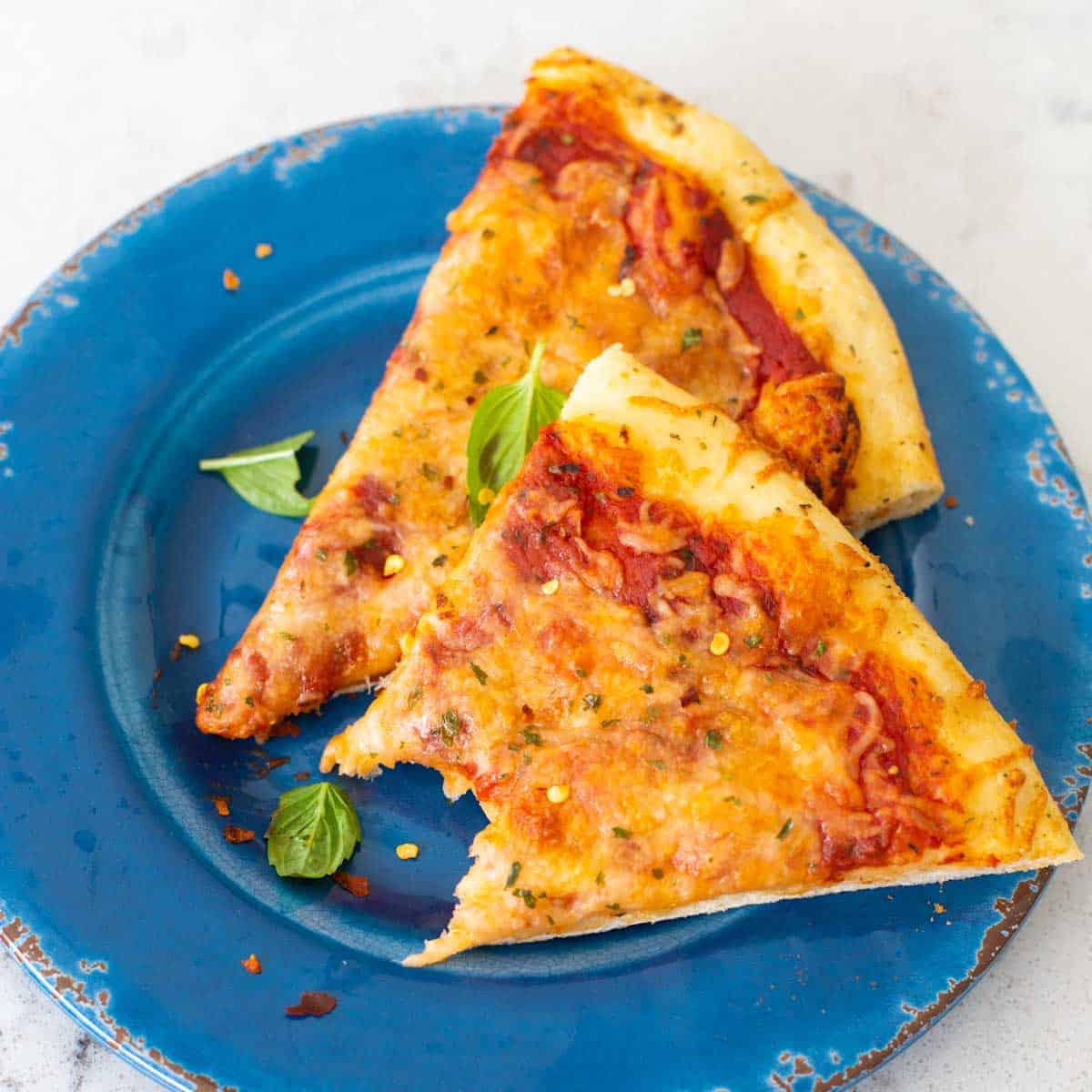 The pizza has been served on a blue plate. A bite has been taken of one piece.