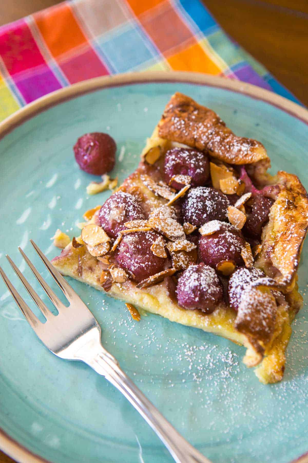 A serving of the fresh cherry clafouti on a blue plate.