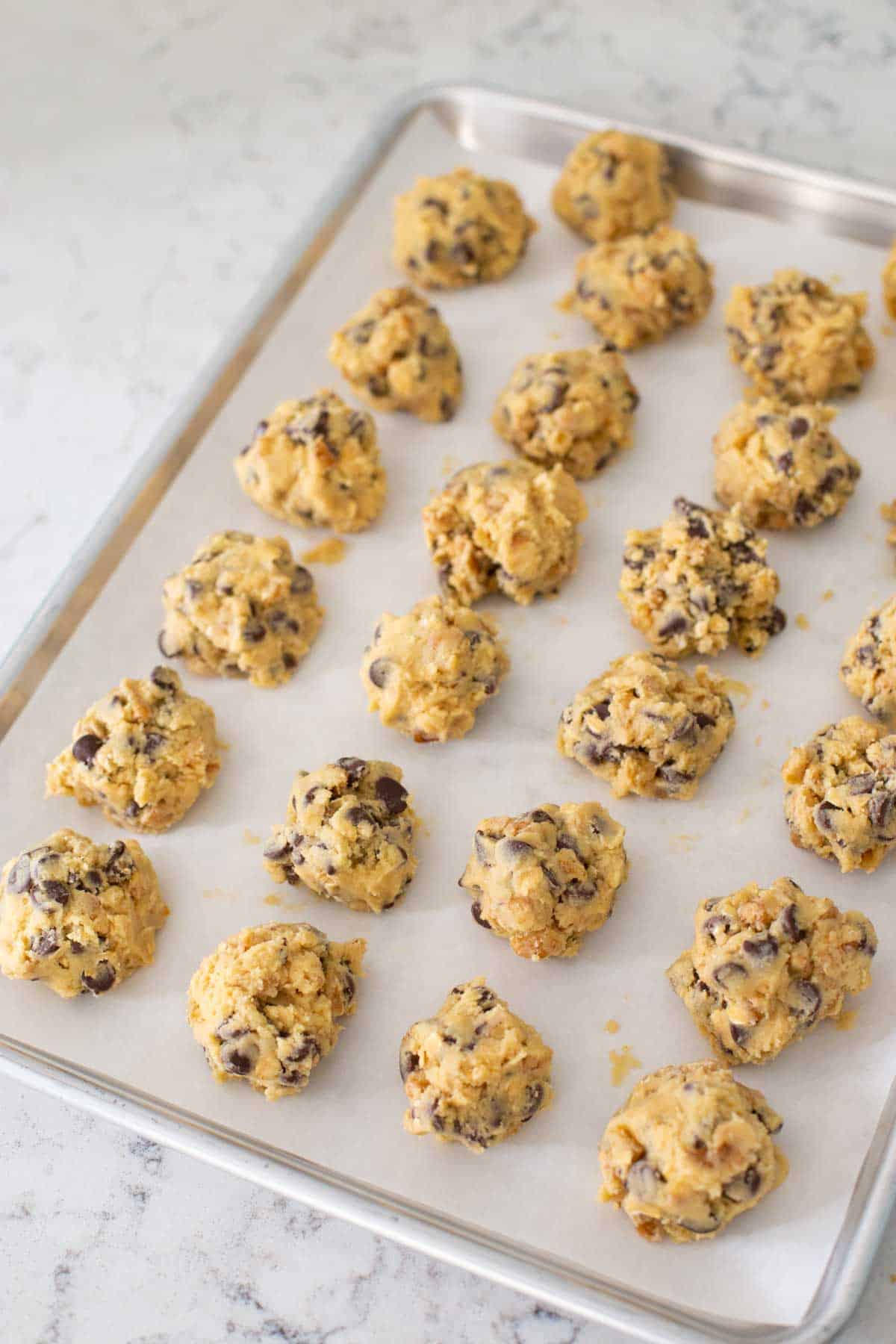 The cookies are on a parchment paper lined baking sheet about to be flash frozen.