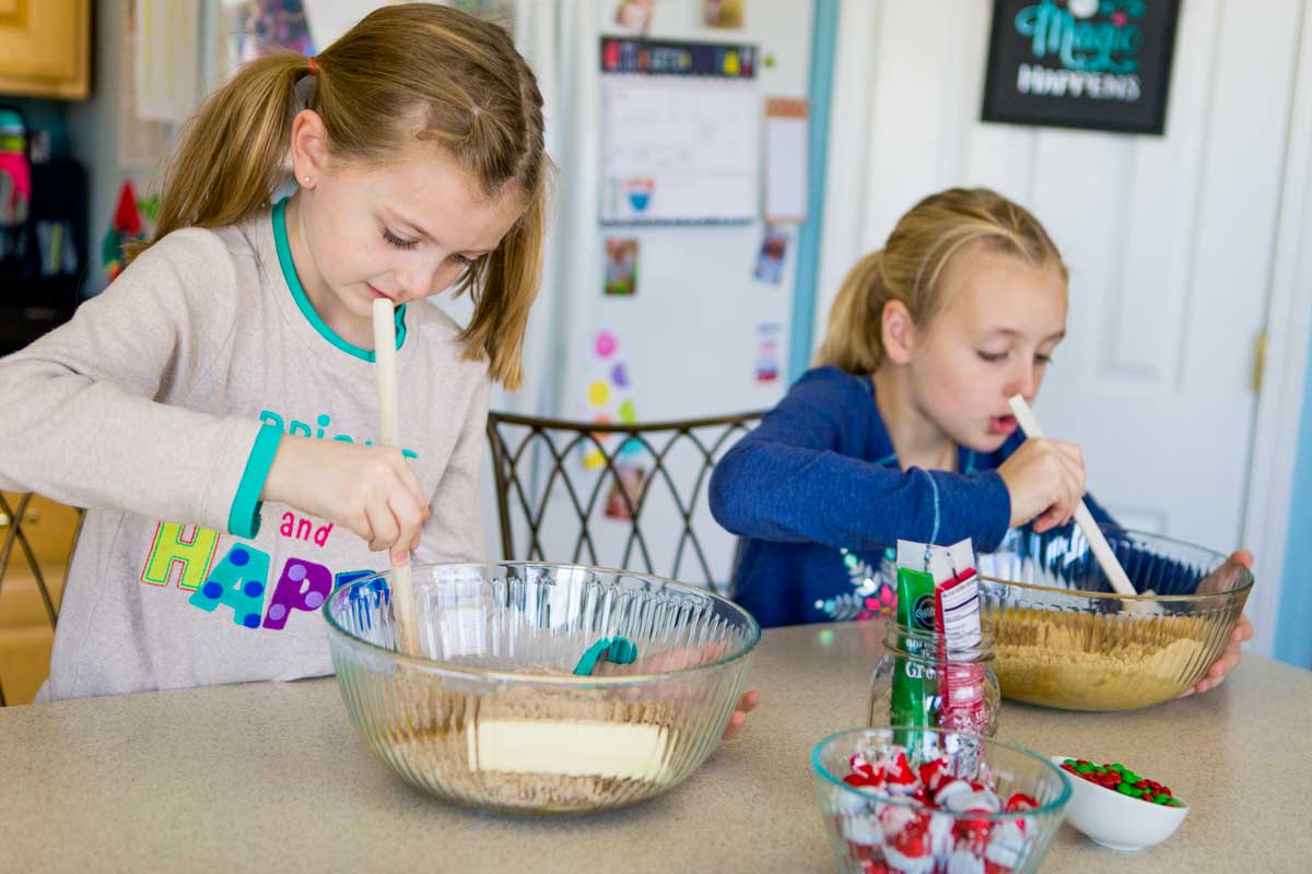 Two young girls baking Christmas cookies in the kitchen.