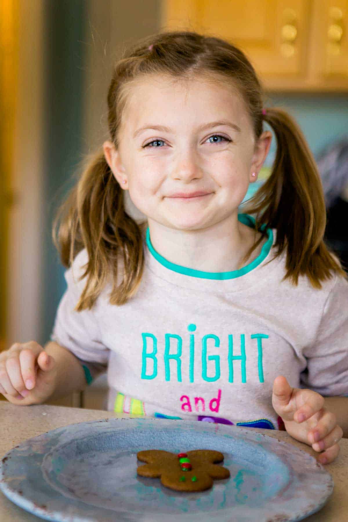 A young girl is about to decorate her cut out cookie.