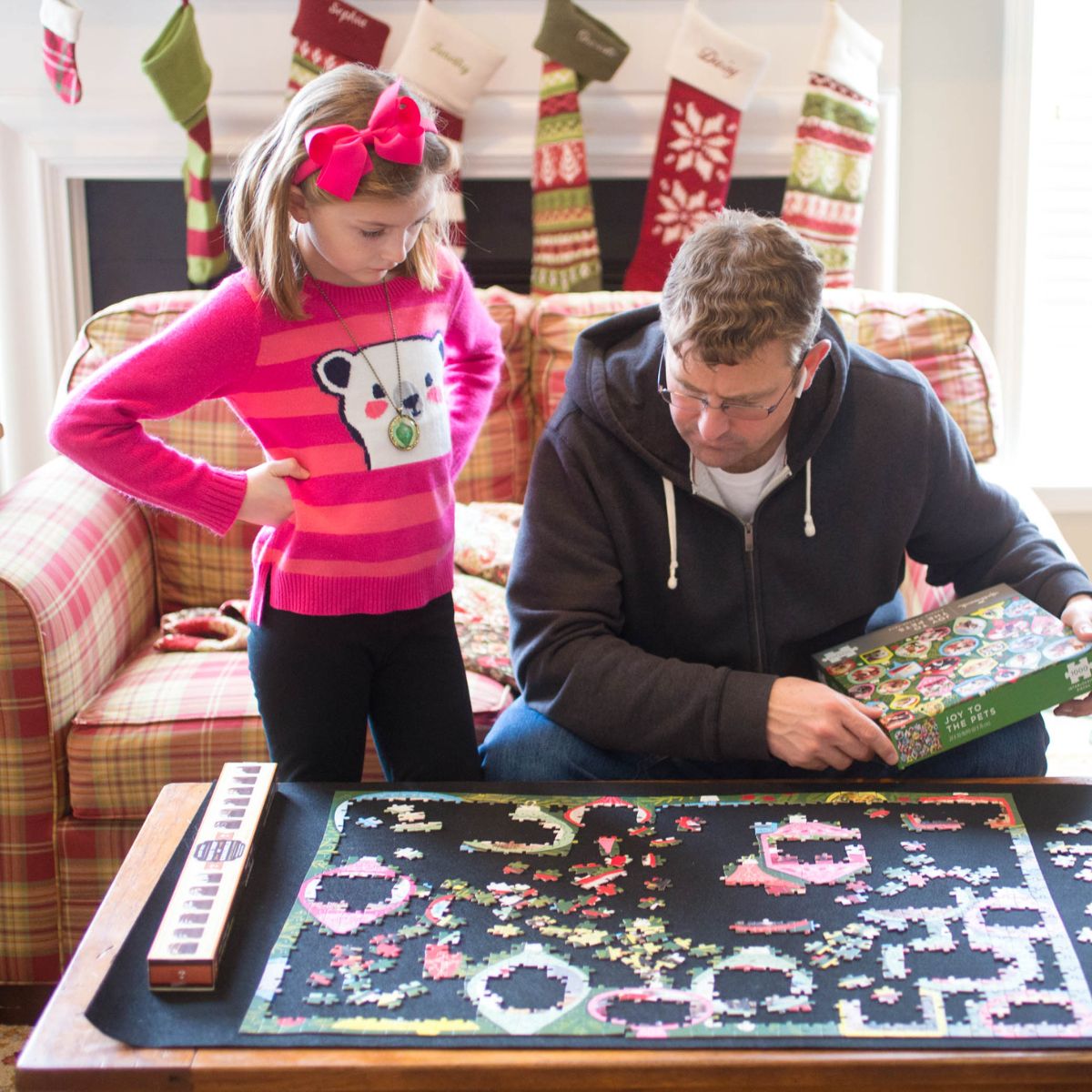 A dad and his daughter work on a Christmas puzzle together