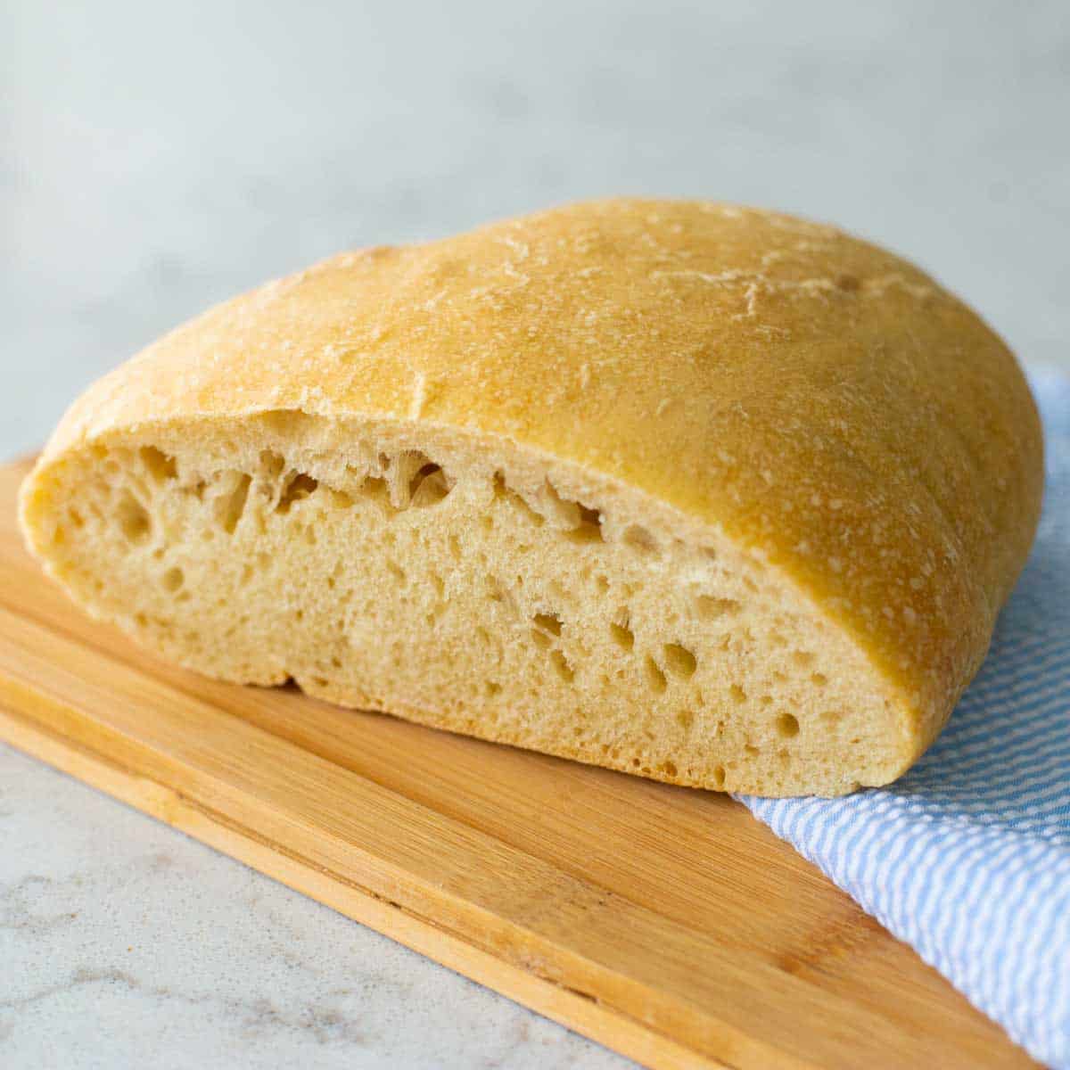 The ciabatta bread is on a cutting board about to be sliced.