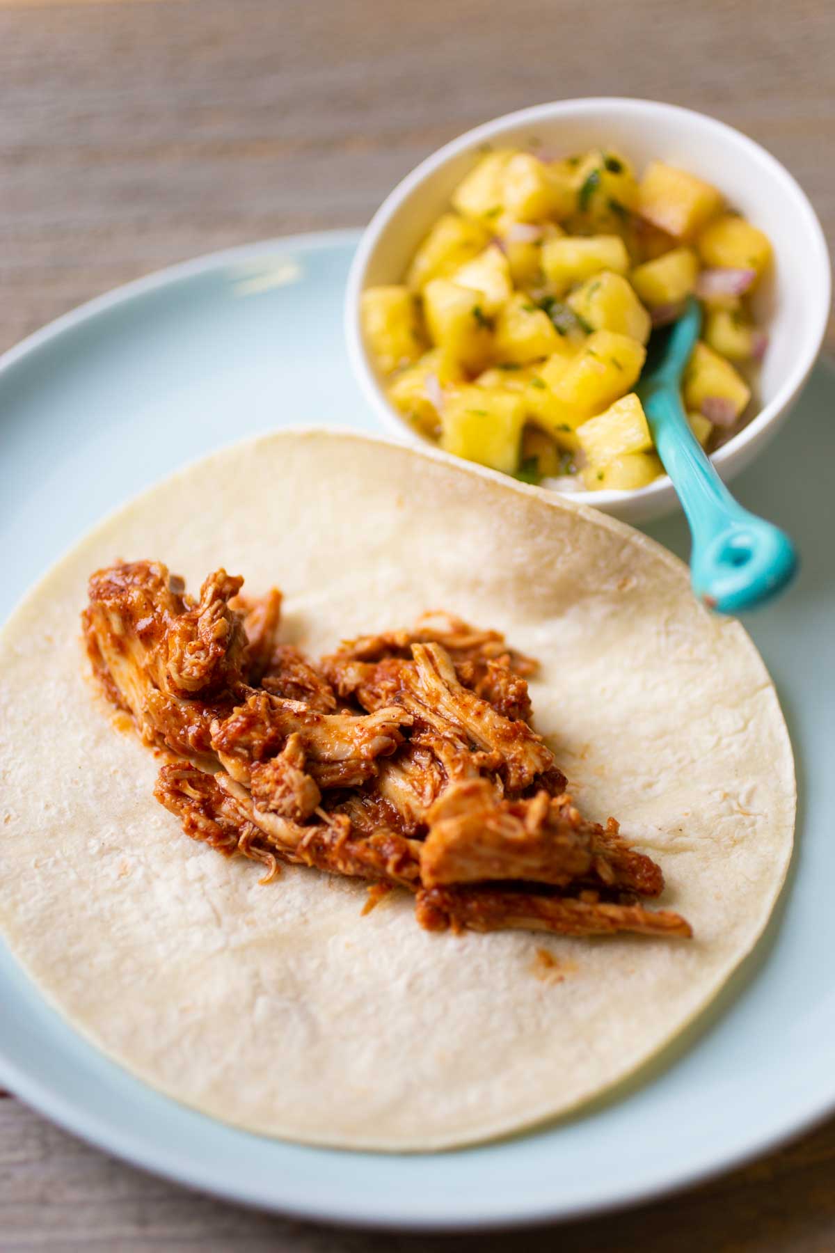 The shredded chicken is on a tortilla shell.