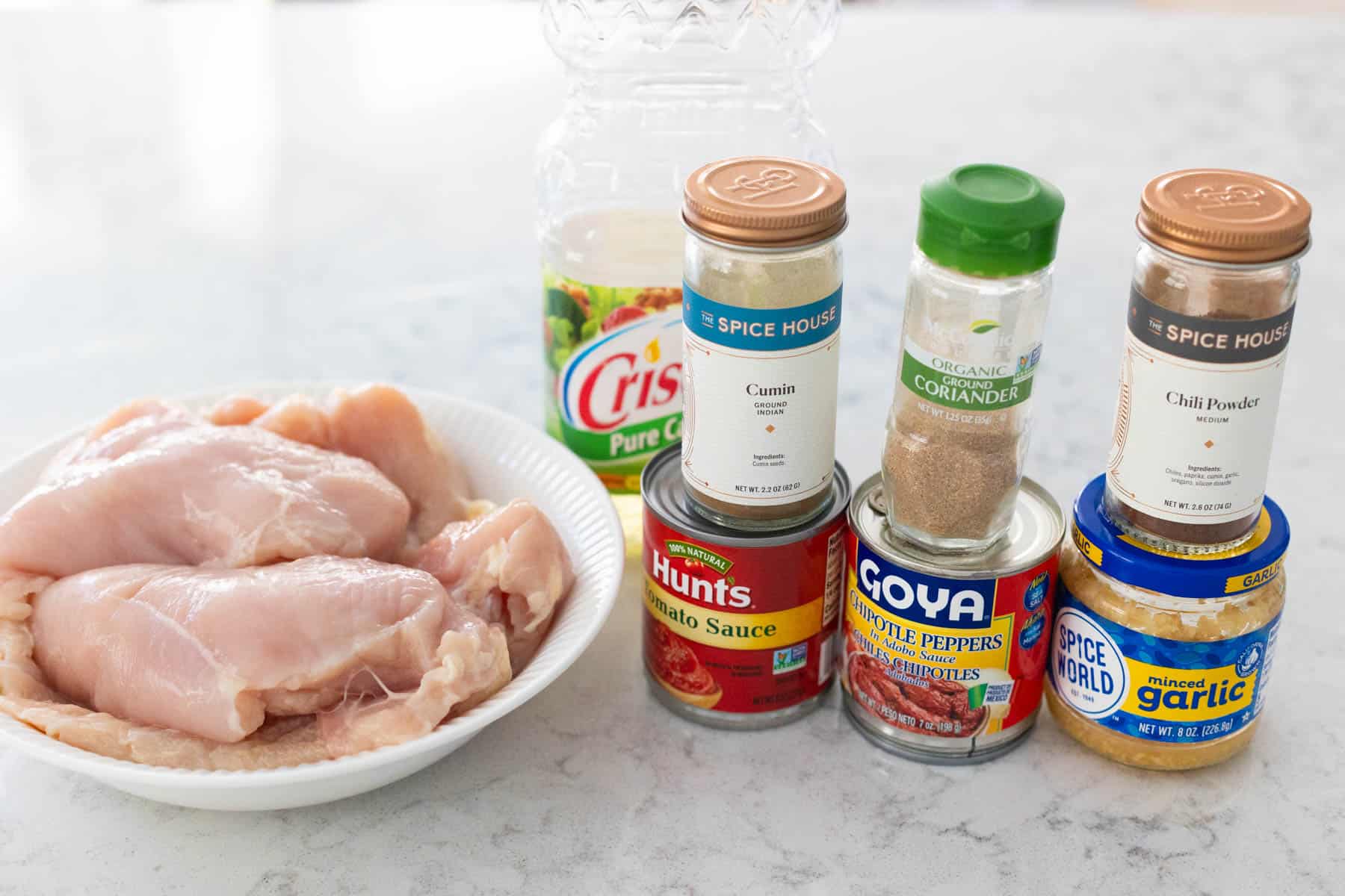 The fresh chicken, seasonings, and tomato sauce are on the counter.