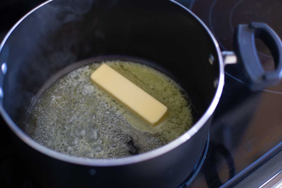 A stick of butter is melting in a large pot.