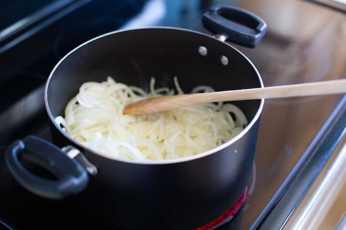 The onions are cooking in the melted butter in the pot.