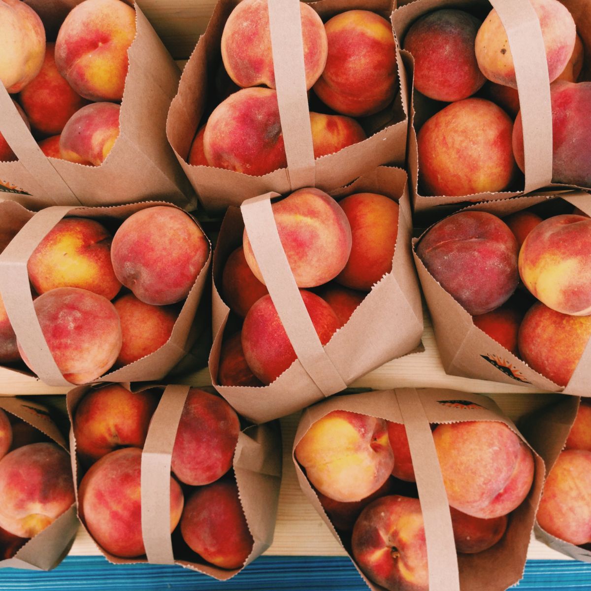 Bags of fresh peaches at a farmer's market stand.