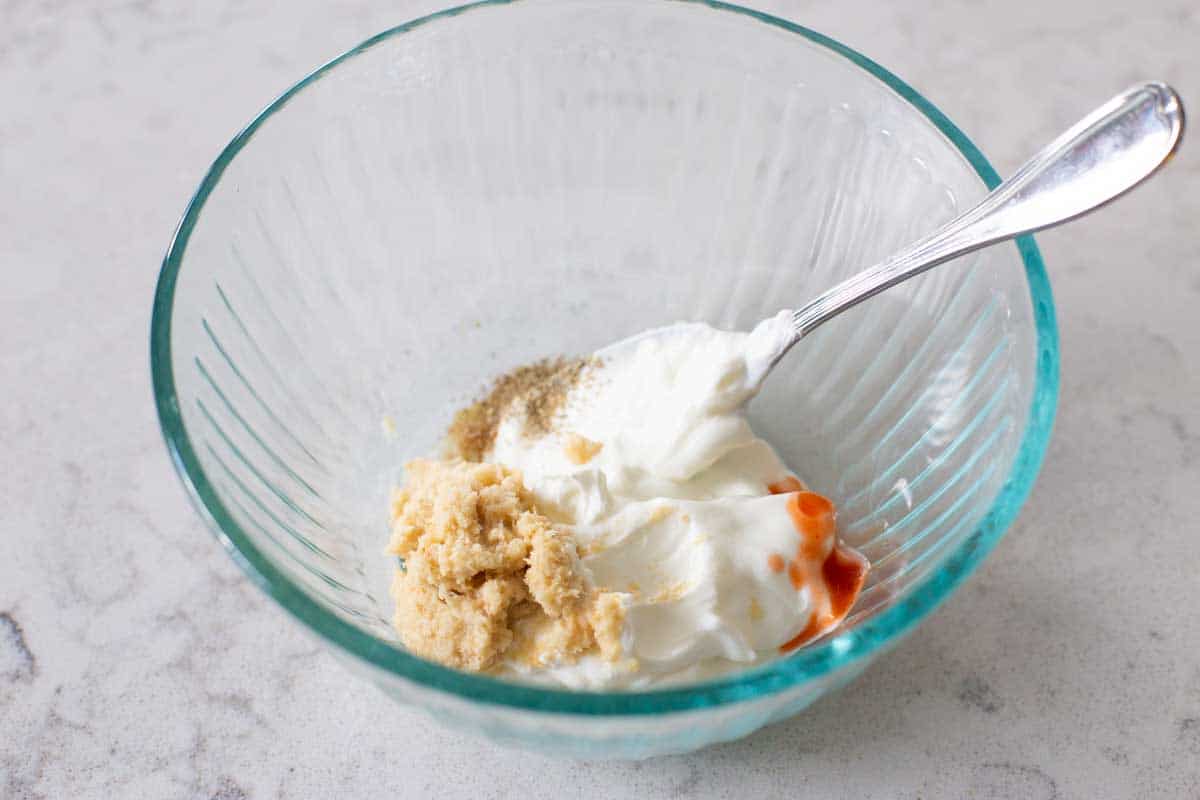 The ingredients have been added to a mixing bowl and a spoon is stirring them together.