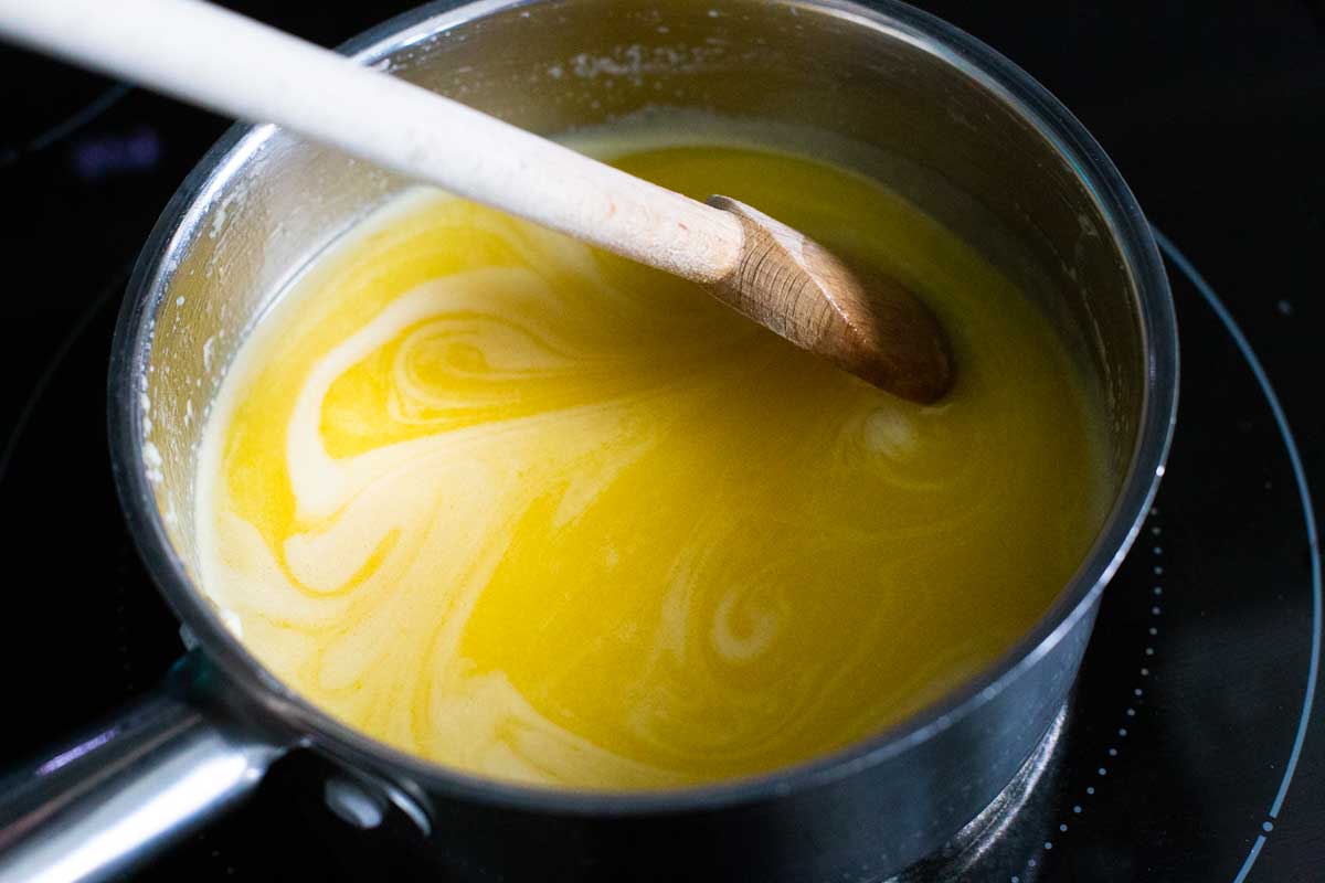 The lemon curd is being stirred in a pan with a spatula.