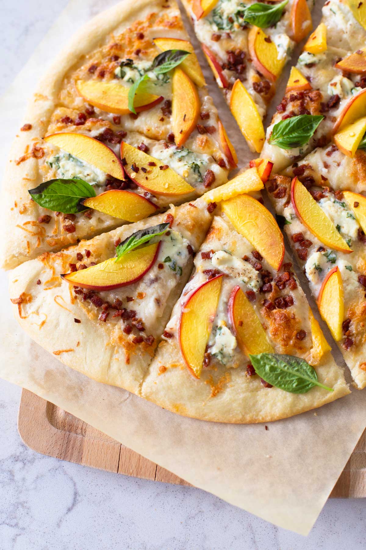 The peach pizza has been baked and sliced for serving.
