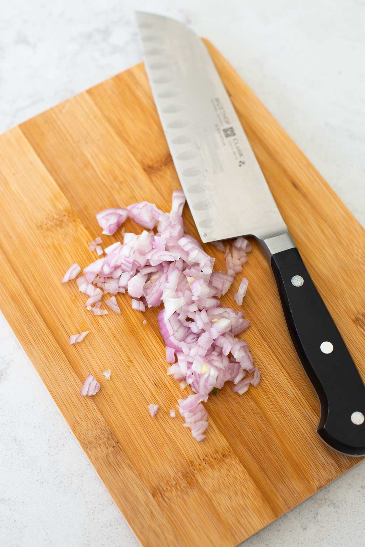 A shallot has been minced by a chef knife.