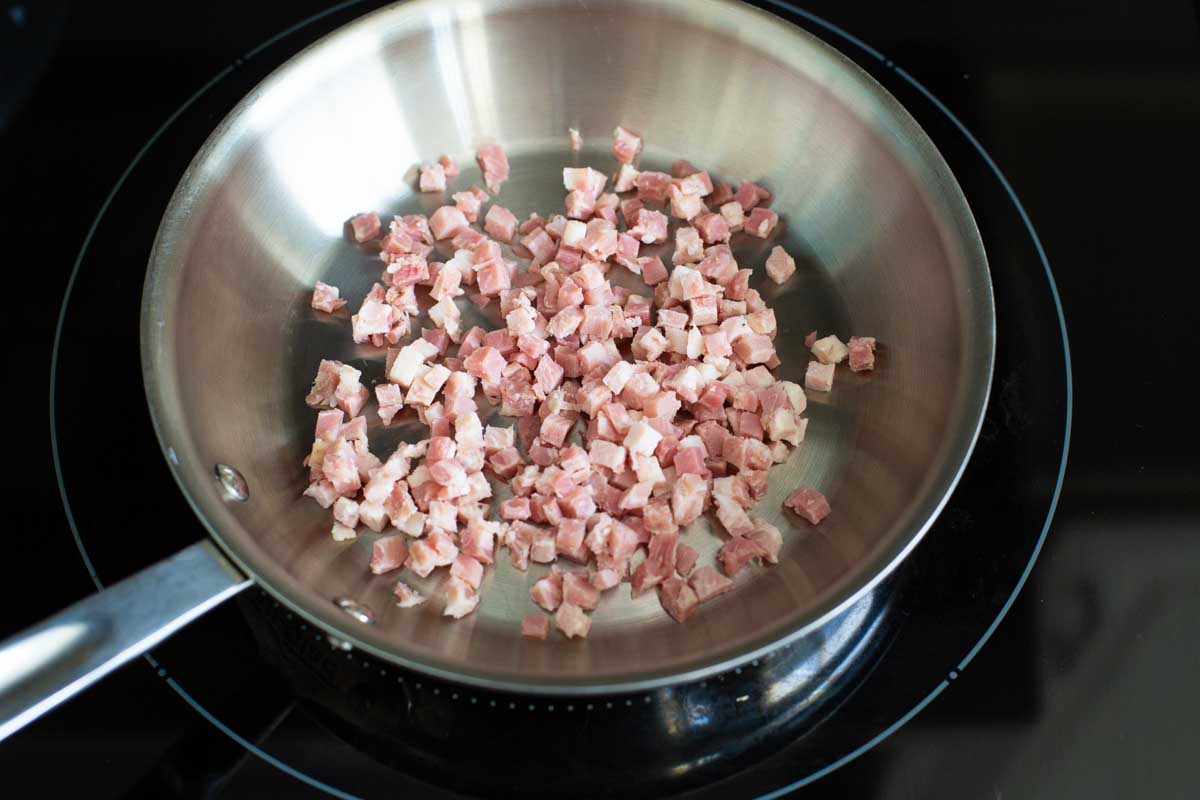 Chopped pancetta is being cooked in a skillet.