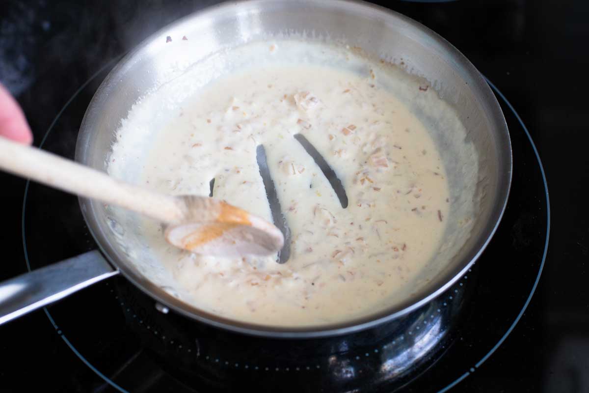 The cream sauce is being finished in the skillet.