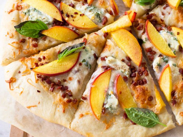 A homemade peach pizza has been sliced and served.