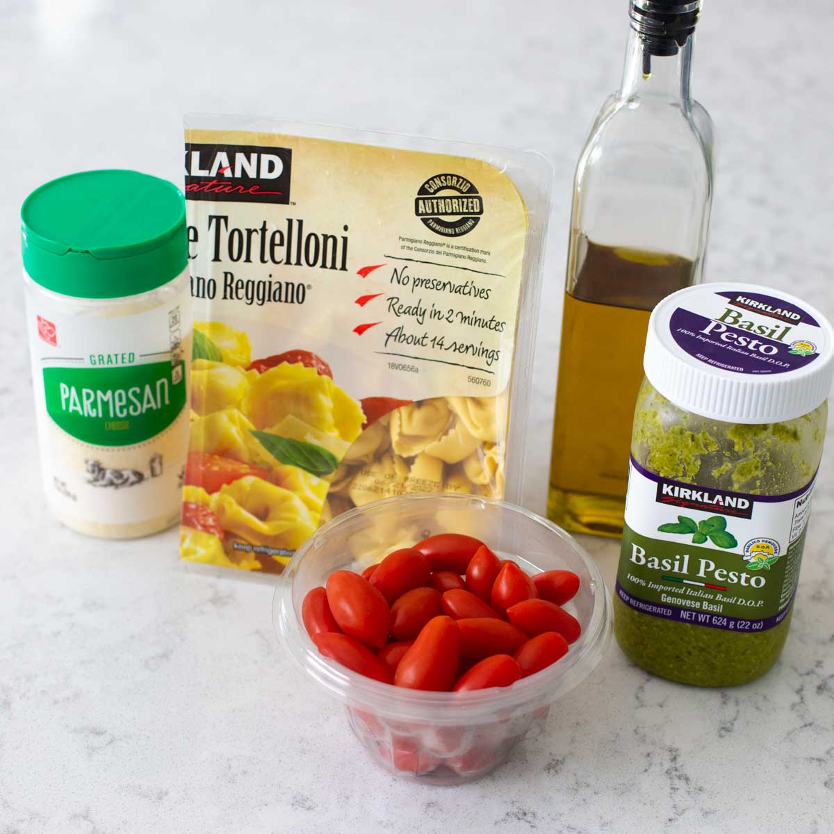 The ingredients to make pesto cheese tortellini are on the counter.