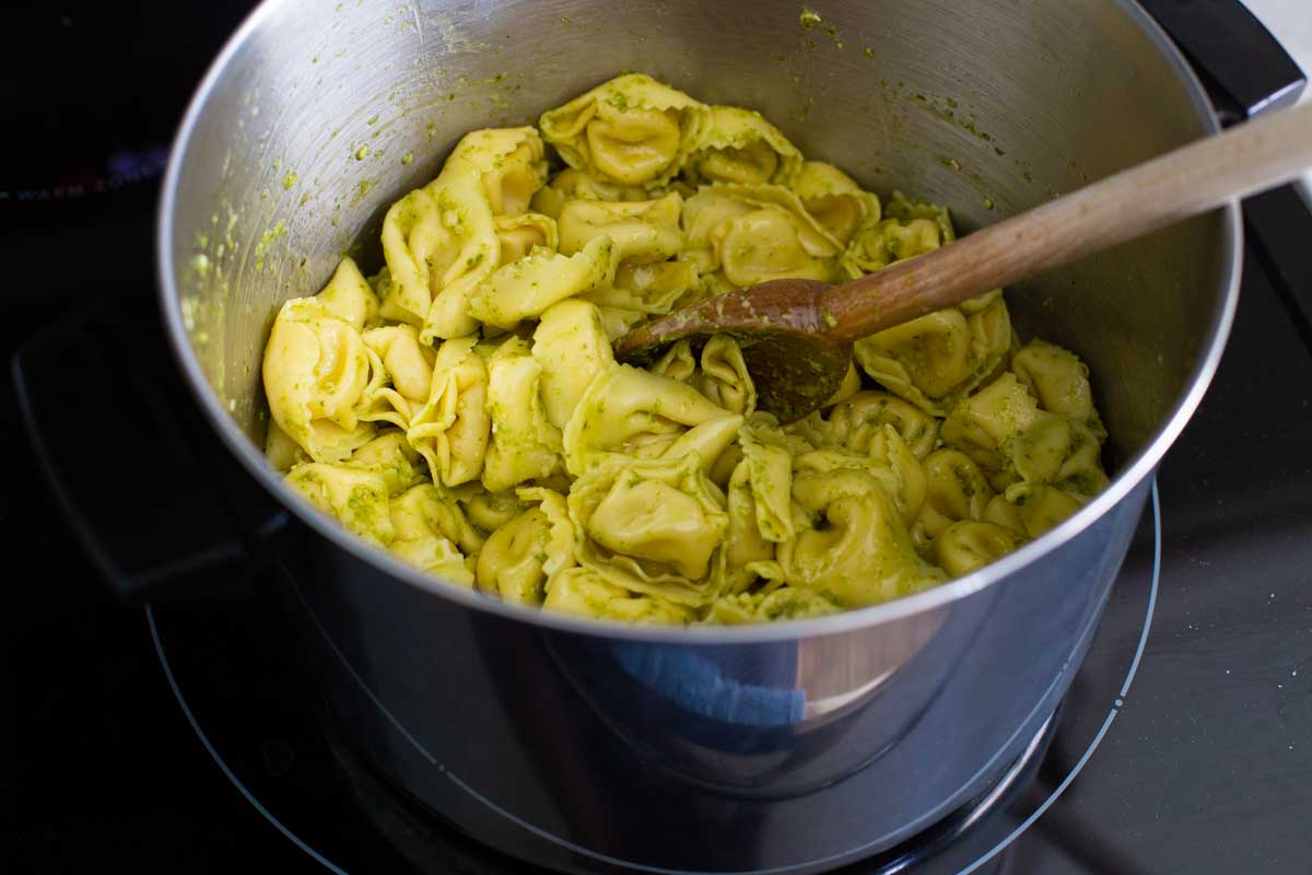 The cheese tortellini have been gently stirred into the pesto sauce.