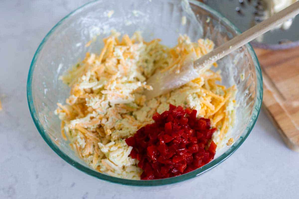 The last step of mixing the pimento cheese, the pimentos are in the mixing bowl.