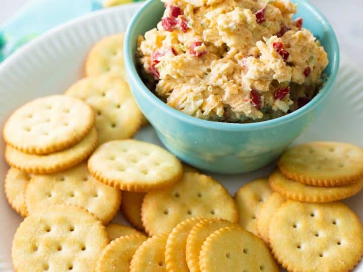 A bowl of homemade pimento cheese is served on a plate with butter crackers.