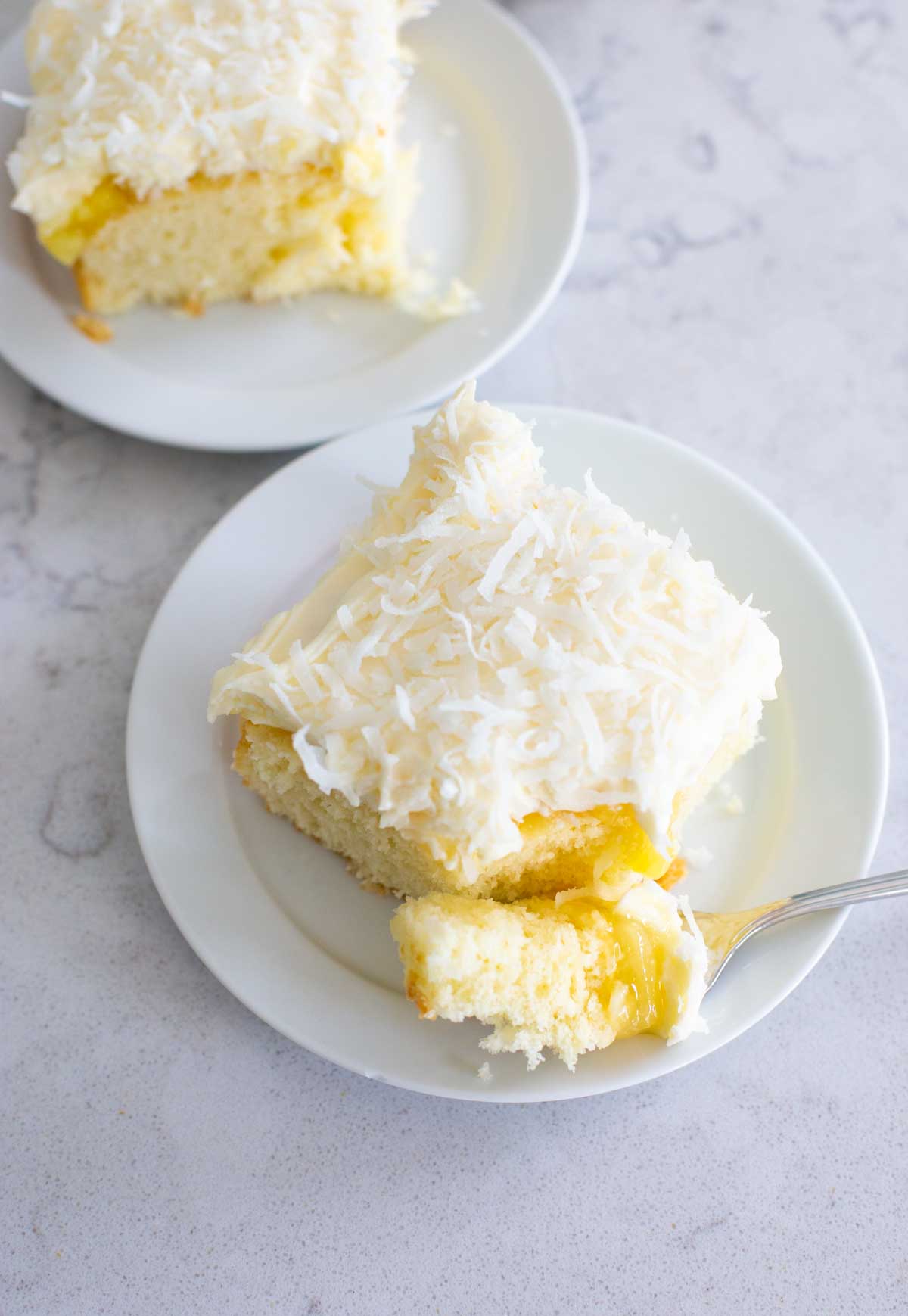 A coconut sheet cake has a layer of pineapple filling under the cream cheese frosting.