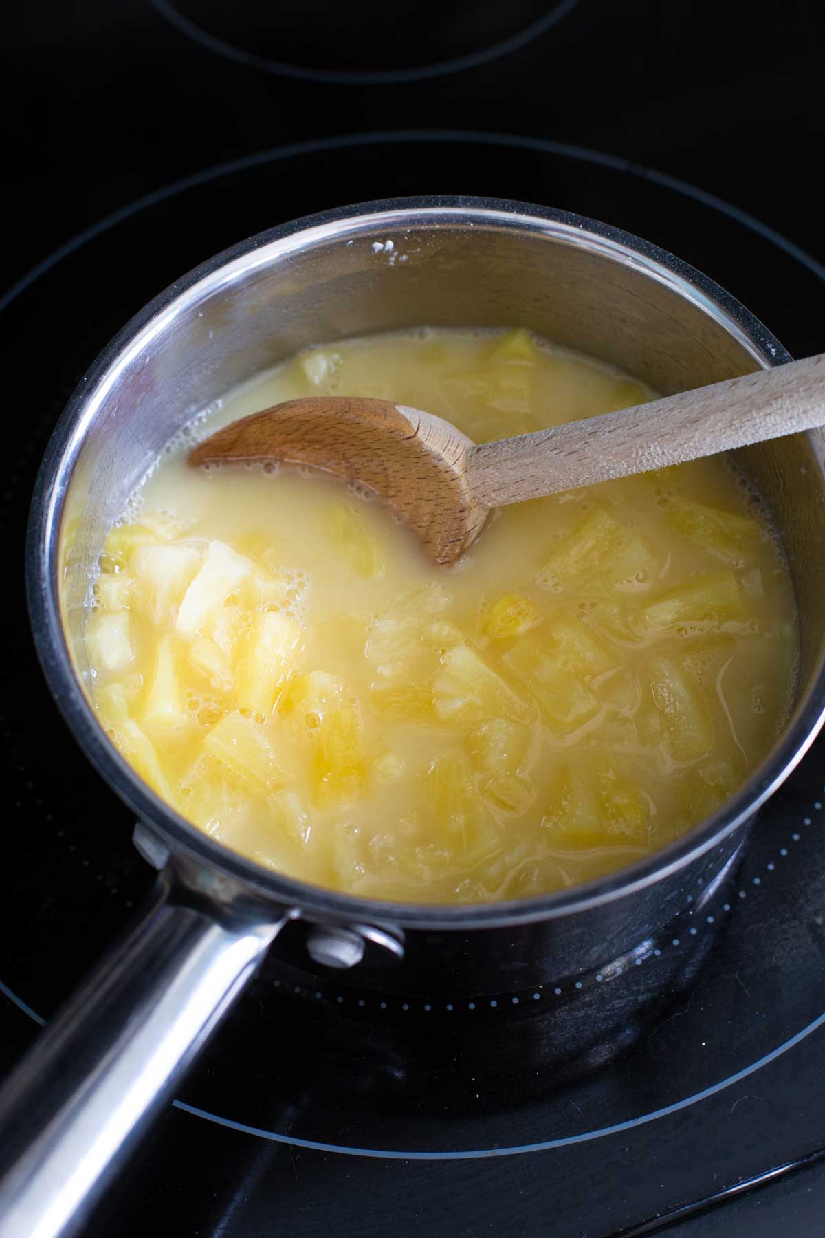 The pot is on a burner and the pineapple filling mixture is coming to a boil.