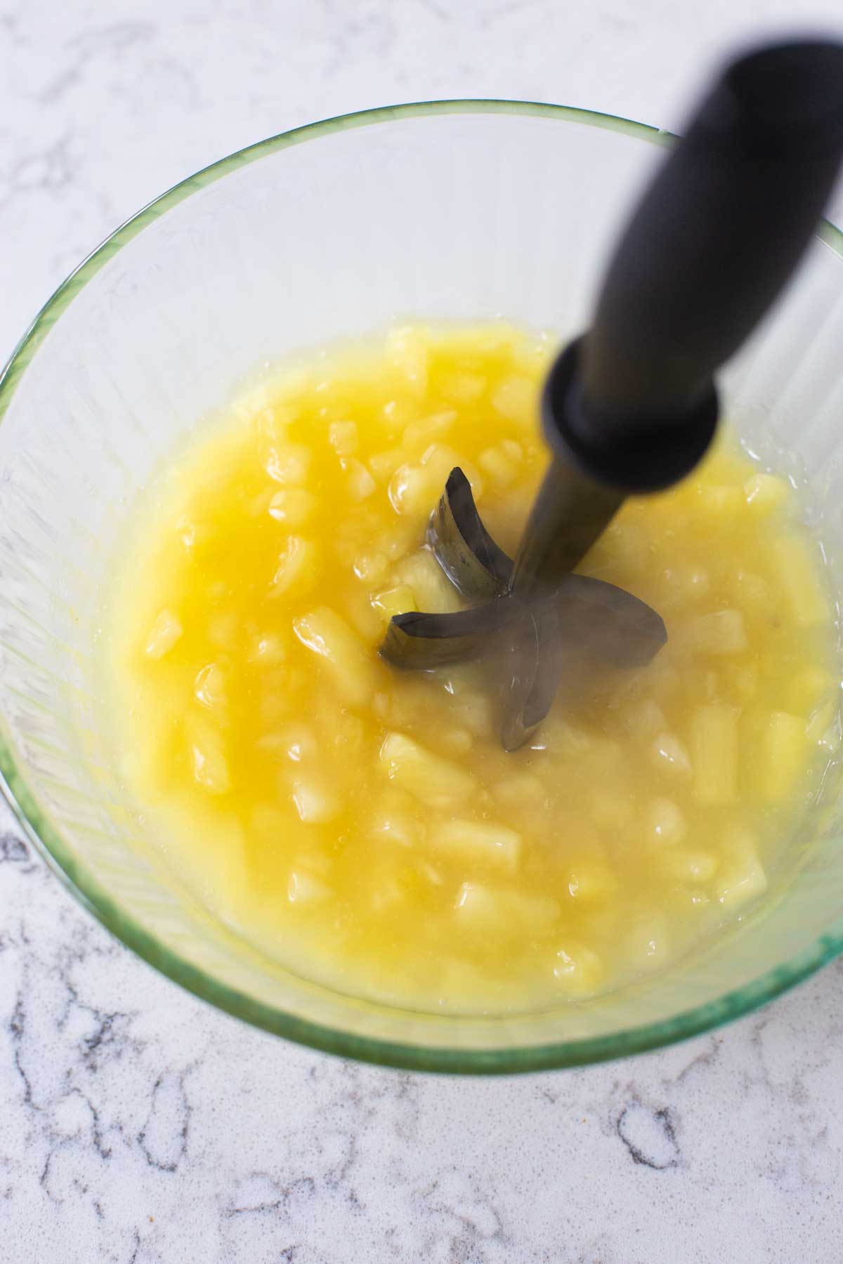 A crushing tool is used to break up the pineapple chunks.