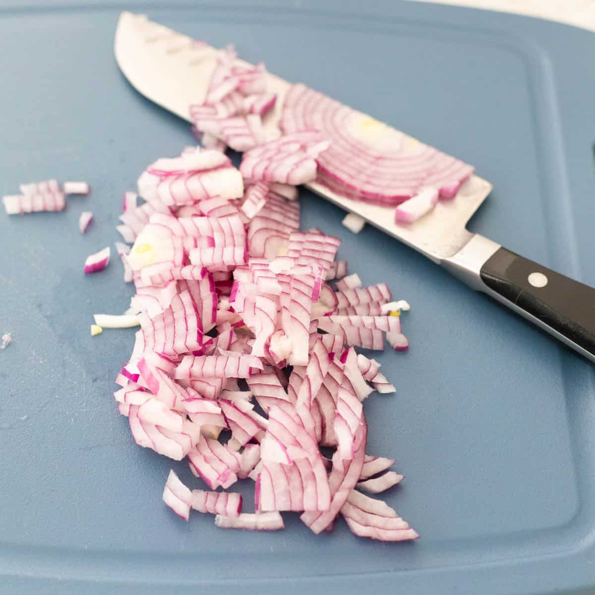 The red onion has been minced on a cutting board.