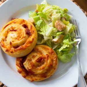 A dinner plate with two pizza buns and caesar salad.
