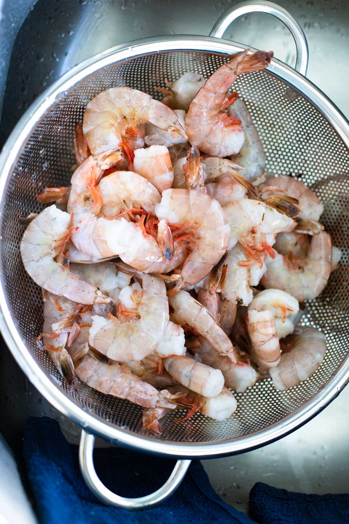 The shrimp are being drained in a large collander.