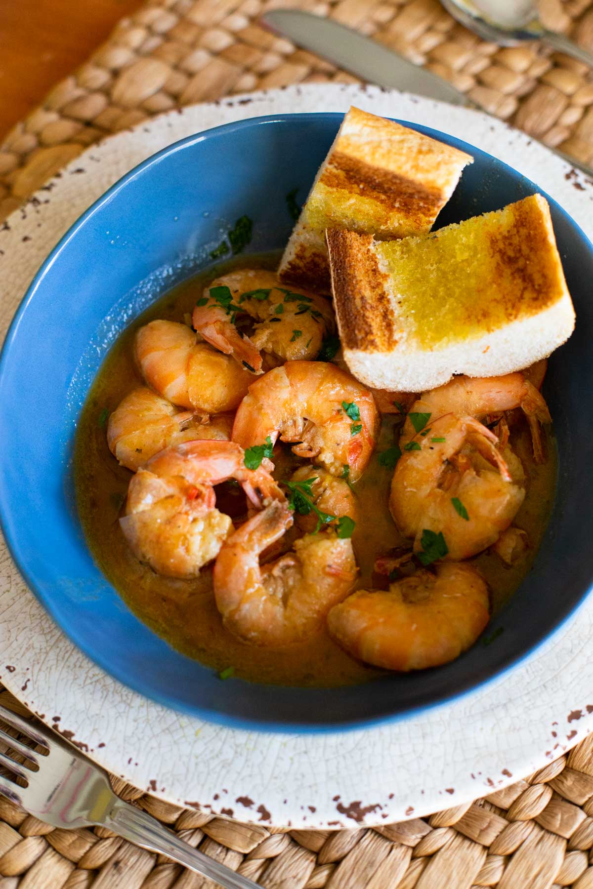 A big bowl of shrimp in butter sauce has garlic toast for dunking.
