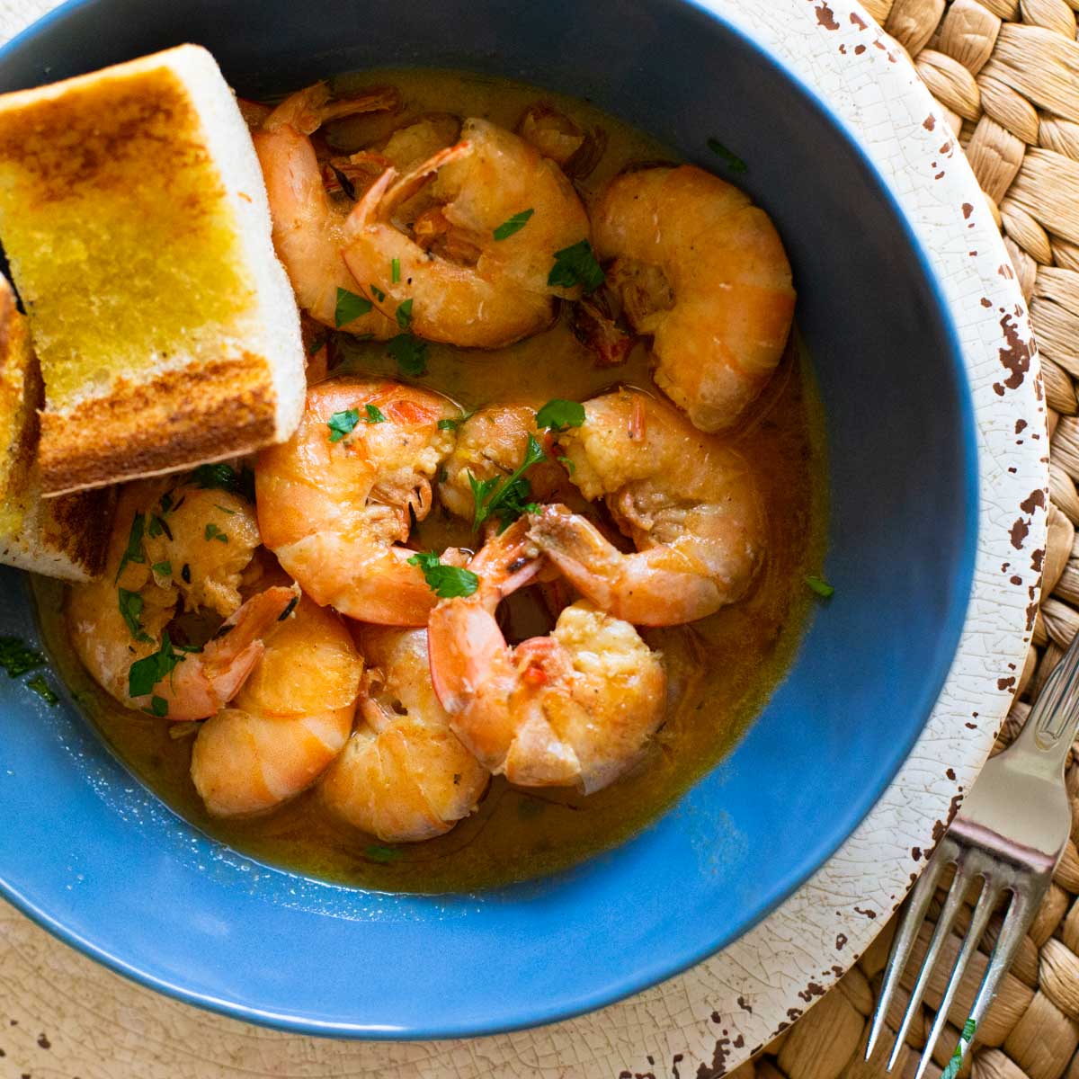 A big bowl of garlic butter shrimp with garlic bread for dunking.