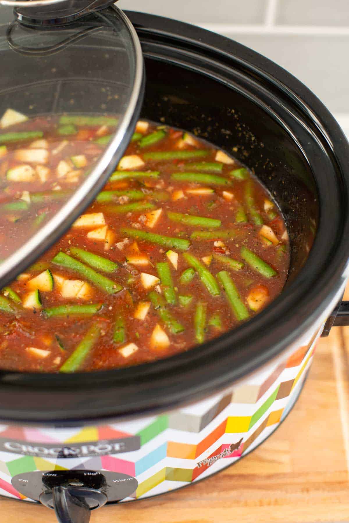 The green beans are floating in the tomato broth inside the slowcooker. 