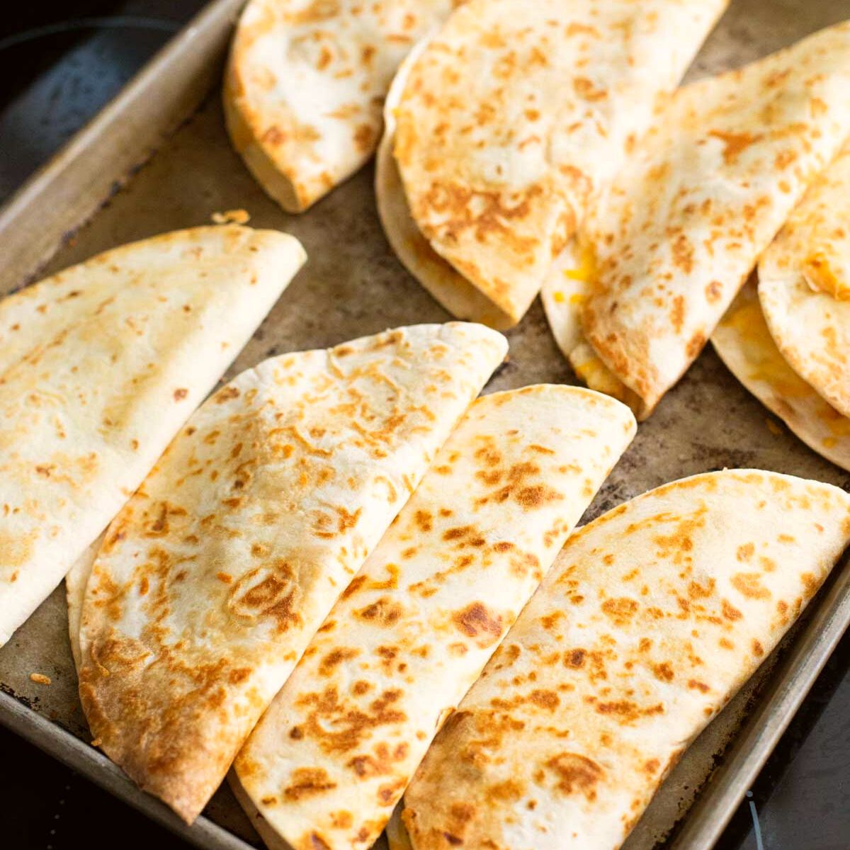 A baking tray filled with baked quesadillas.